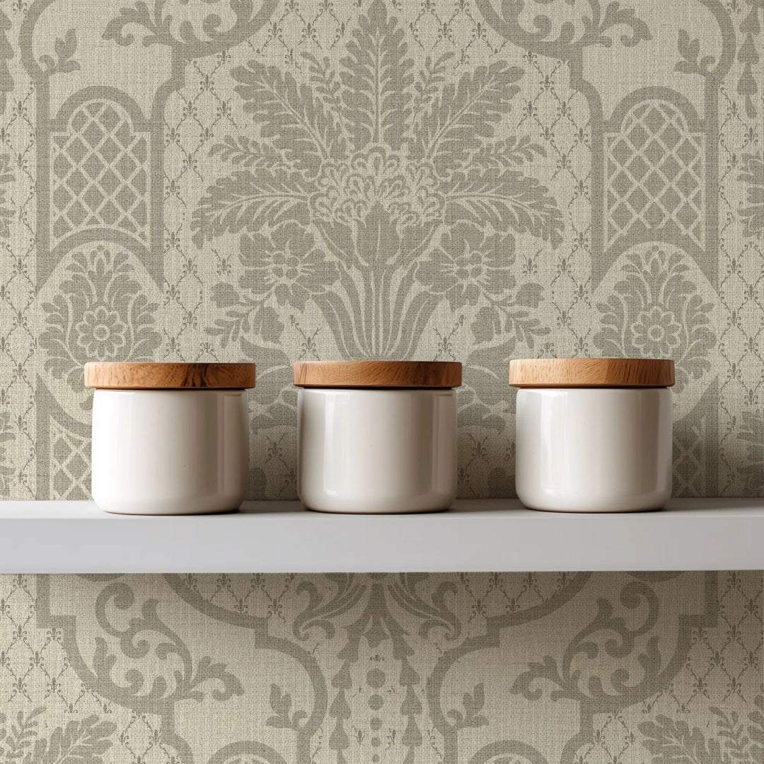 Three white ceramic canisters with light natural wood lids arranged on a white shelf against a beige damask wallpaper background.