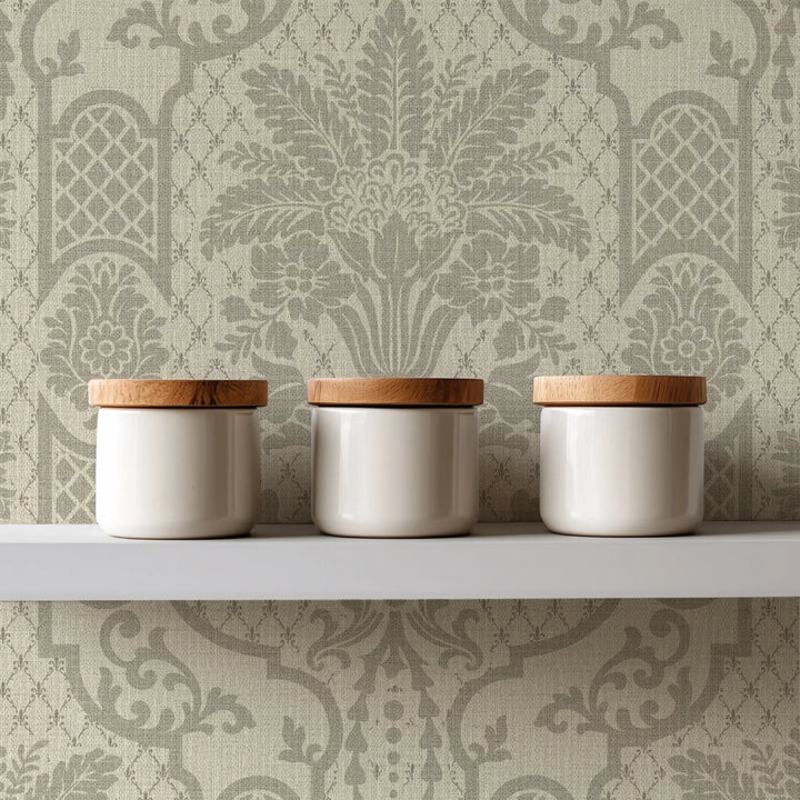 Three white ceramic canisters with light natural wood lids arranged on a white shelf against a beige damask wallpaper background.